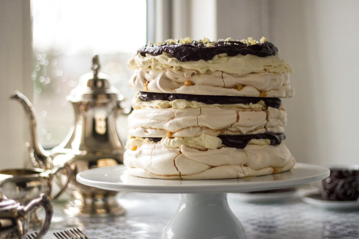 Side shot of meringue cake on stand with tea pot in background