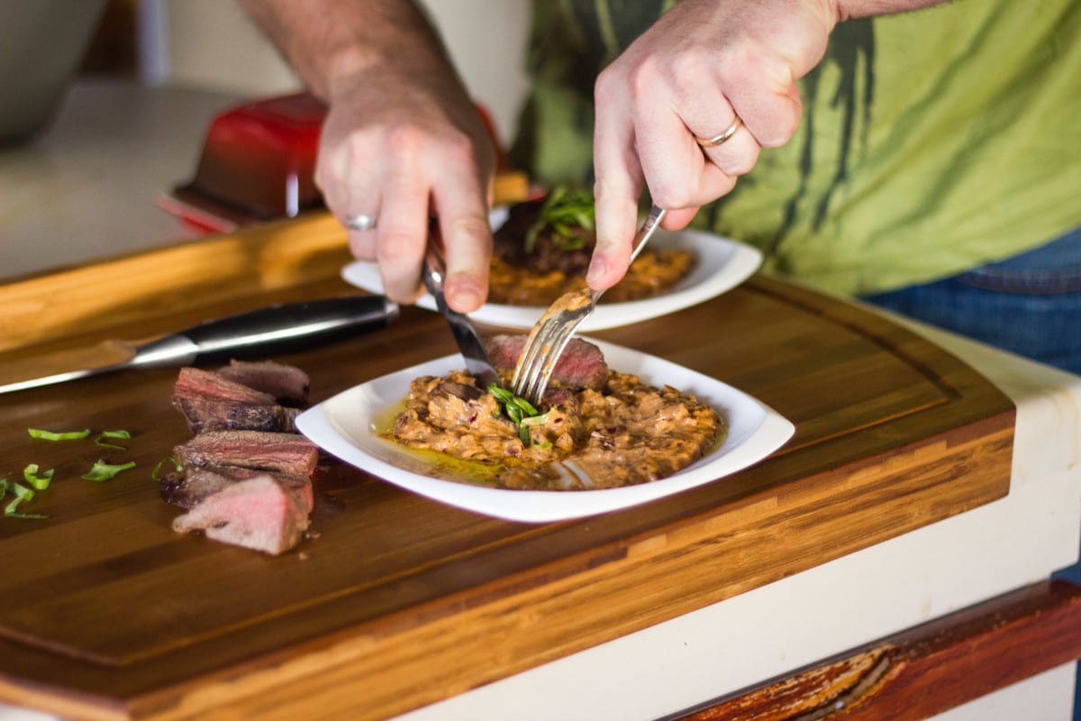 Side shot of steak being cut on wooden cutting board