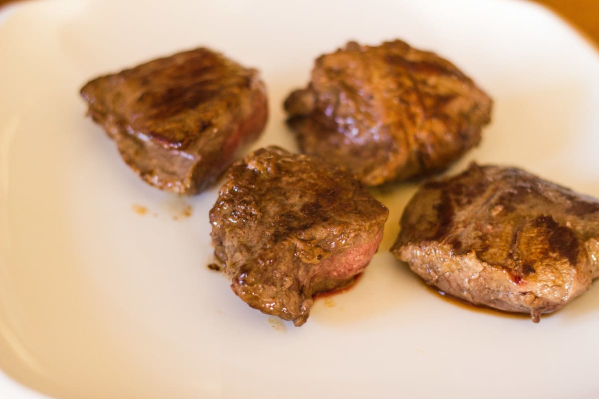 Side shot of cut browned steak on white plate