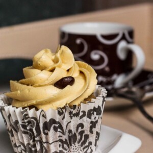 Close-up of a cupcake with coffee in the background