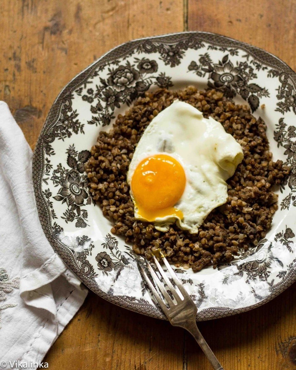 Top down of a cooked buckwheat of black and white plate with an egg on top
