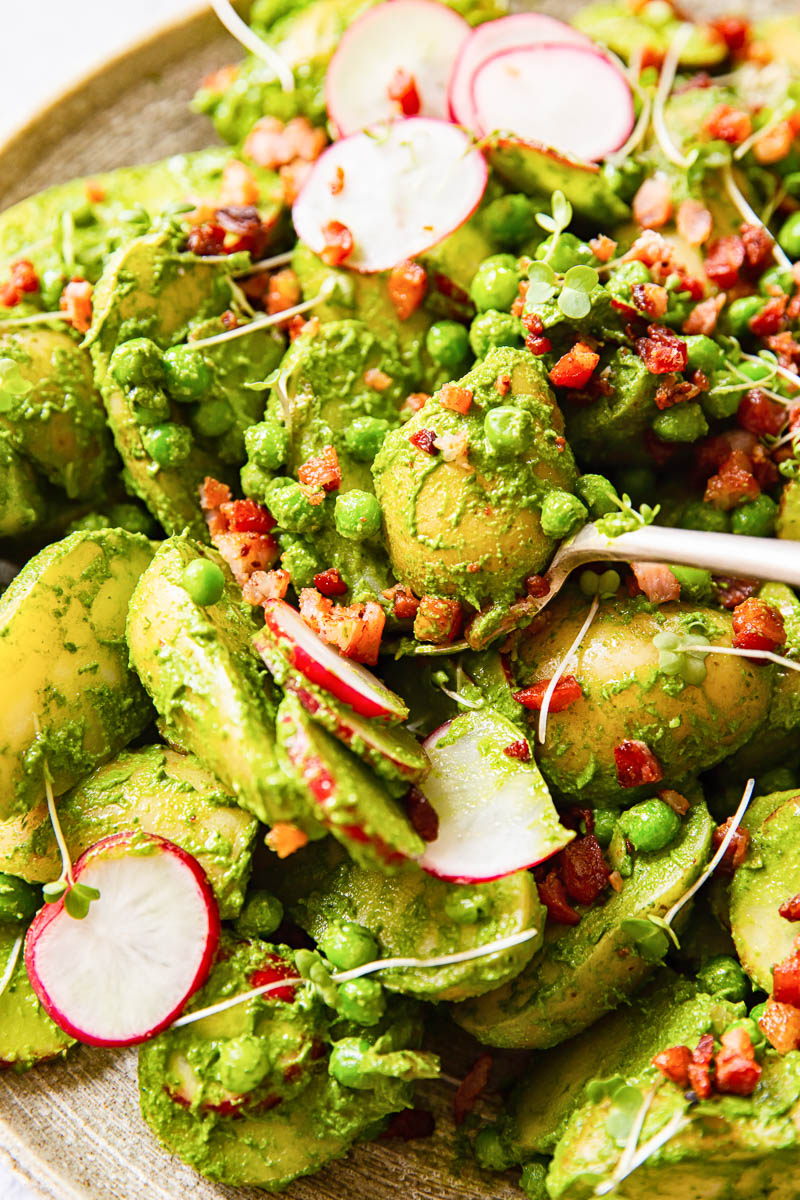 Pesto potato salad with sliced radishes, peas and bacon