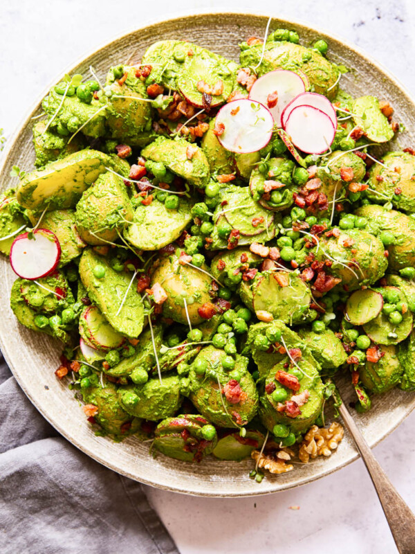 Potato and bacon salad in a bowl with spinach and pesto