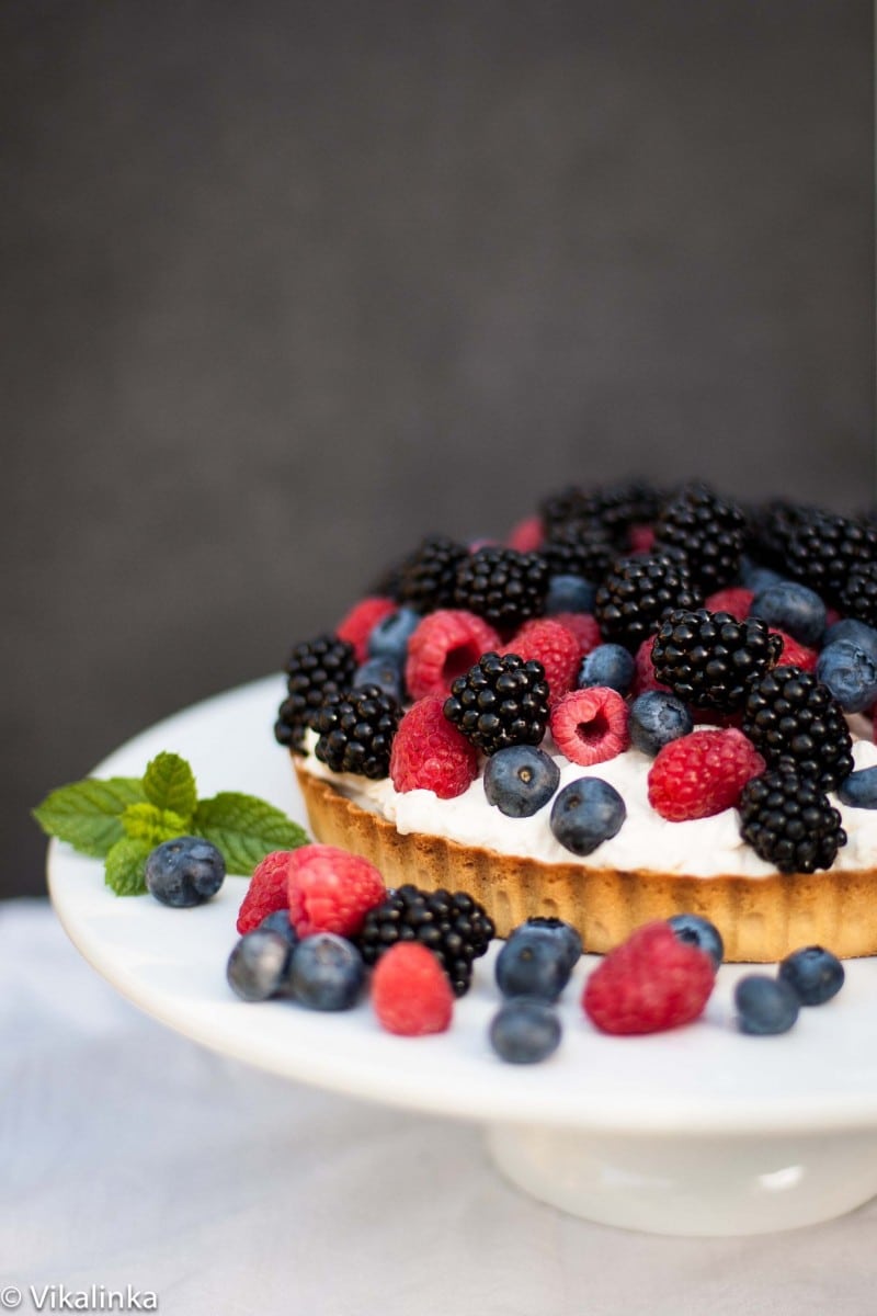Side shot of tart with blueberries, blackberries and raspberries in front