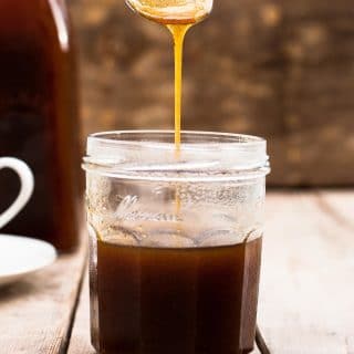 Spoon pouring pumpkin spice syrup into a jar