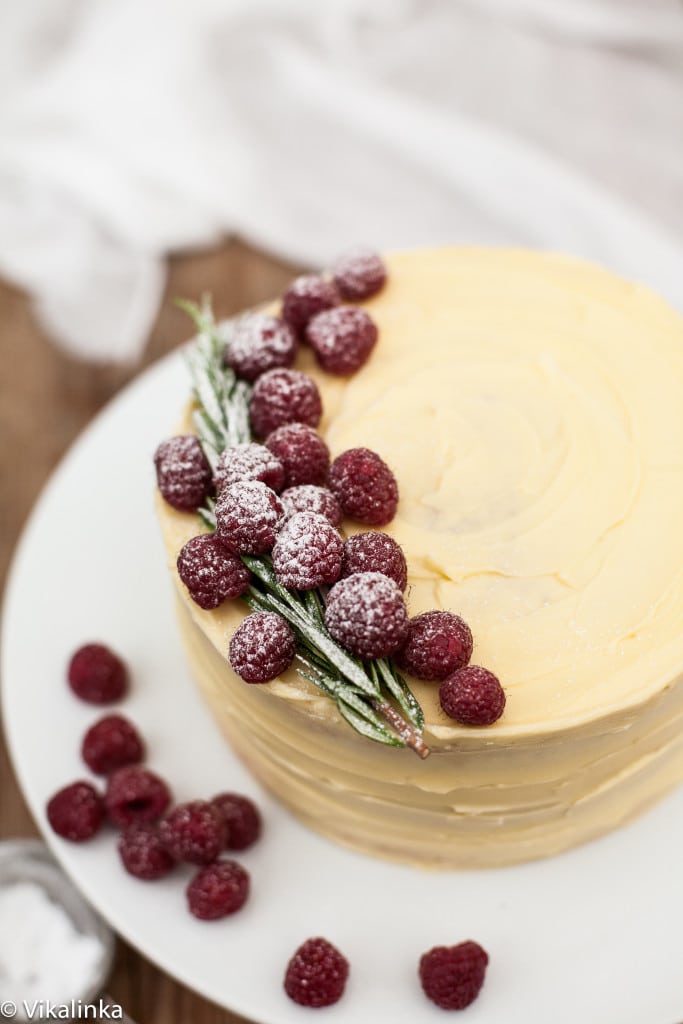 Top down view of the frostbitten raspberry cake with berries and rosemary sprig