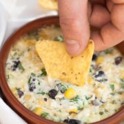 a chip being dipped in a cheesy dip