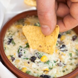 a chip being dipped in a cheesy dip