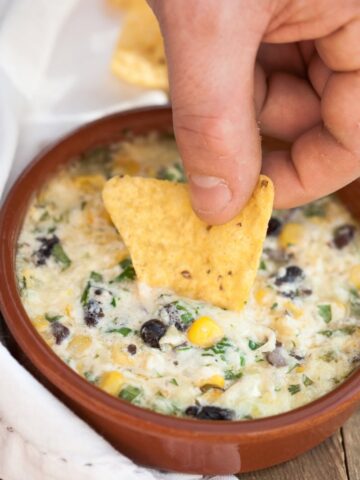 a chip being dipped in a cheesy dip