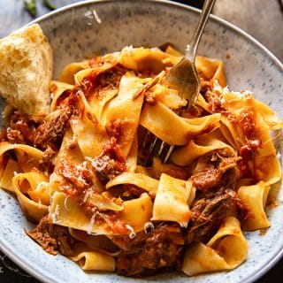 Bowl of Rustic Italian Beef Ragu with a piece of chunky bread and a fork