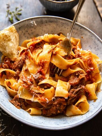 Bowl of Rustic Italian Beef Ragu with a piece of chunky bread and a fork