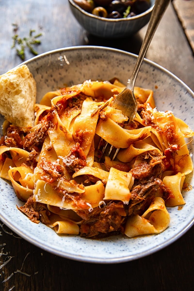 Bowl of Rustic Italian Beef Ragu with a piece of chunky bread and a fork