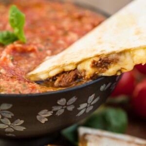 quesadilla being dipped in salsa