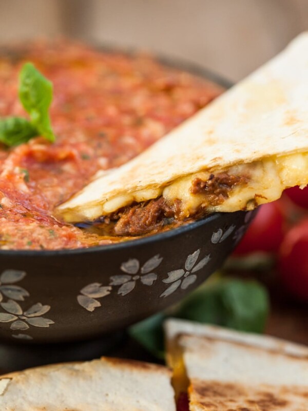 quesadilla being dipped in salsa