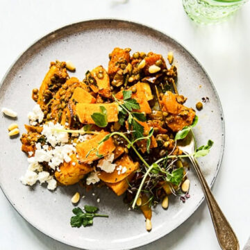 top down view of roasted squash, lentils and feta on grey plate