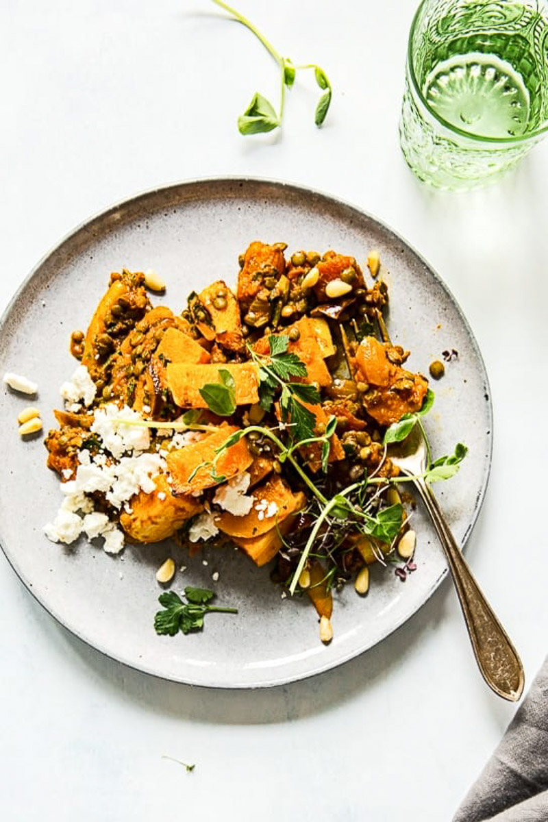 top down view of roasted squash, lentils and feta on grey plate