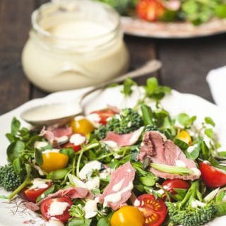 plate of salad with dressing behind in a jar