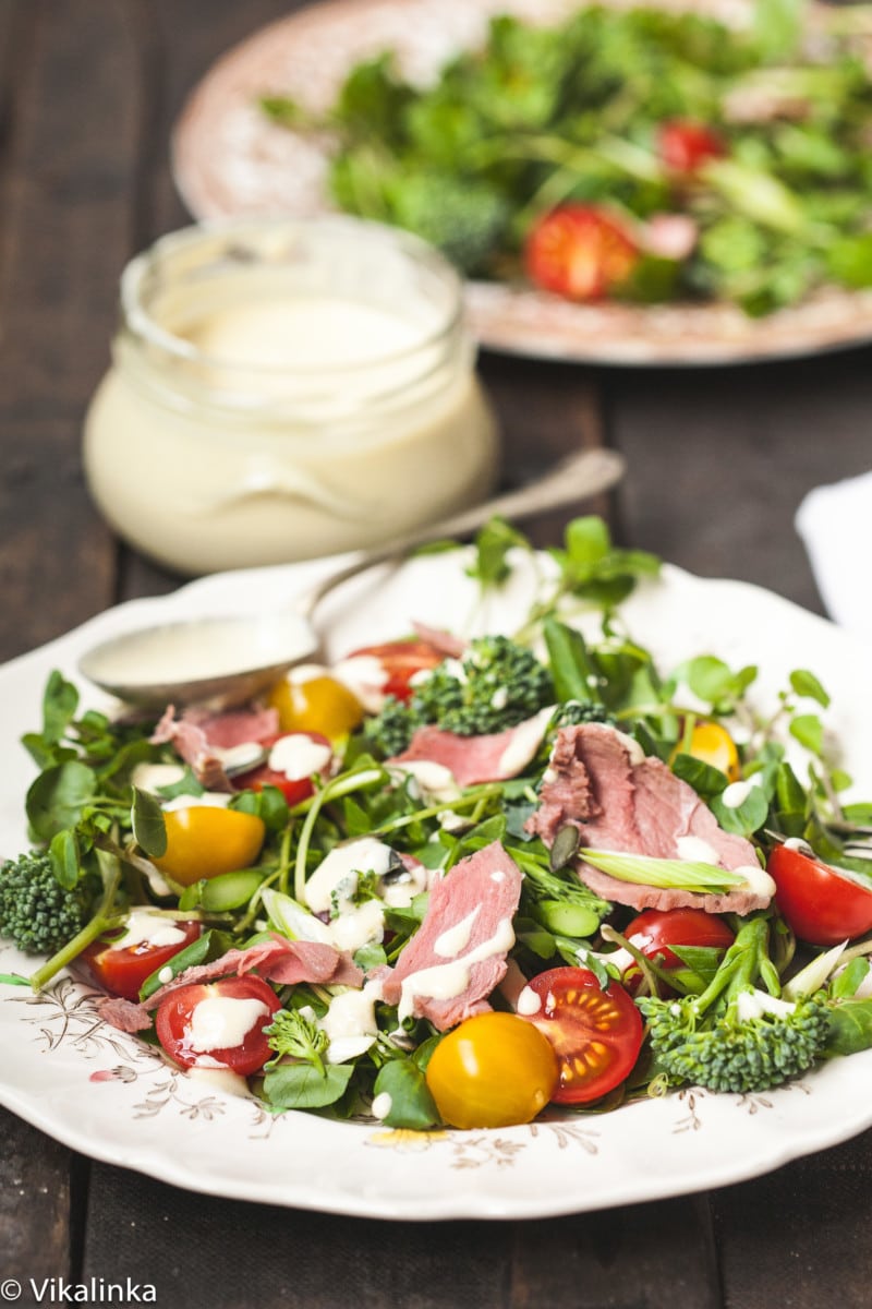 plate of salad with dressing behind in a jar