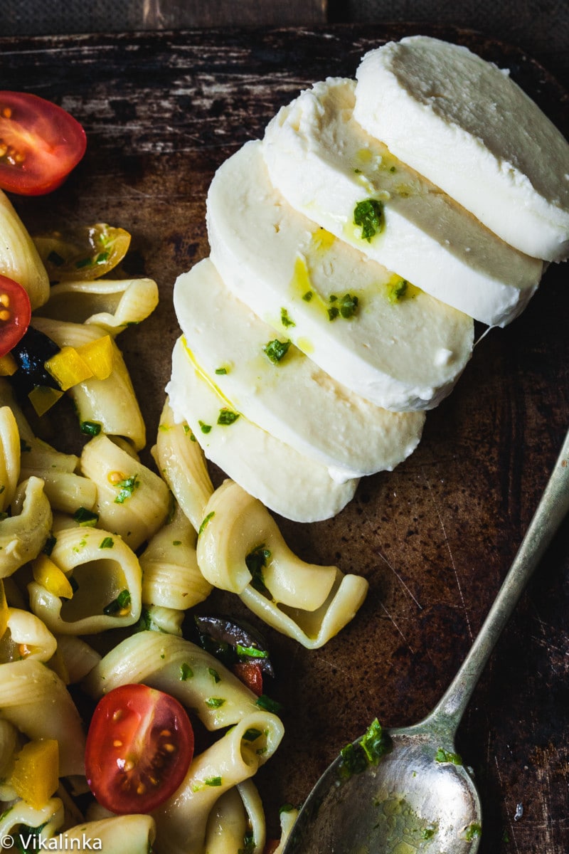 sliced fresh mozzarella on dark background and pasta salad