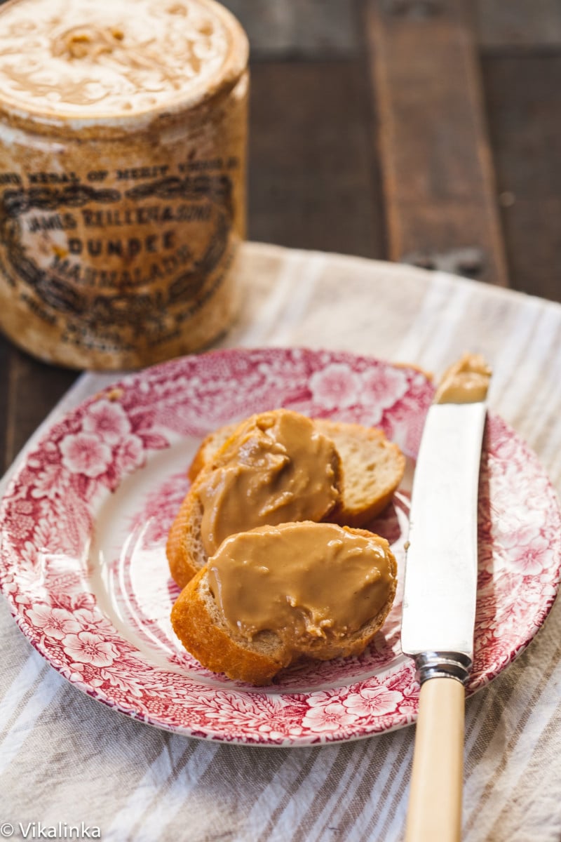 two slices of baguette covered with peanut butter on a plate, butter knife