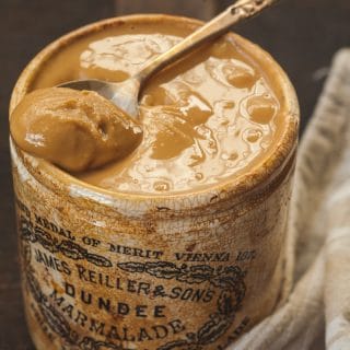 peanut butter in a brown jar with a spoon in it