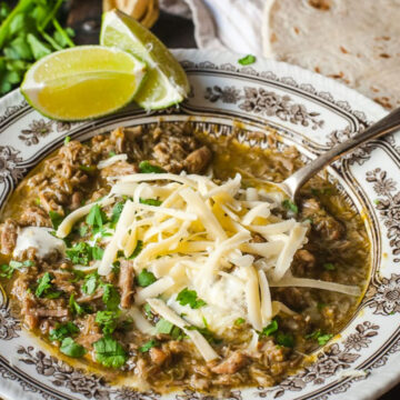 Chili Verde in a bowl topped with grated cheese and chopped cilantro