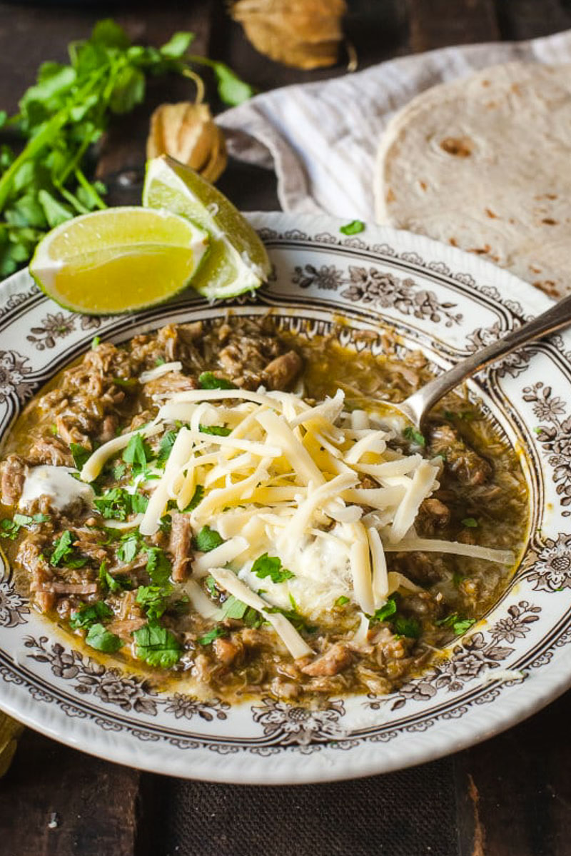 Chili Verde in a bowl topped with grated cheese and chopped cilantro