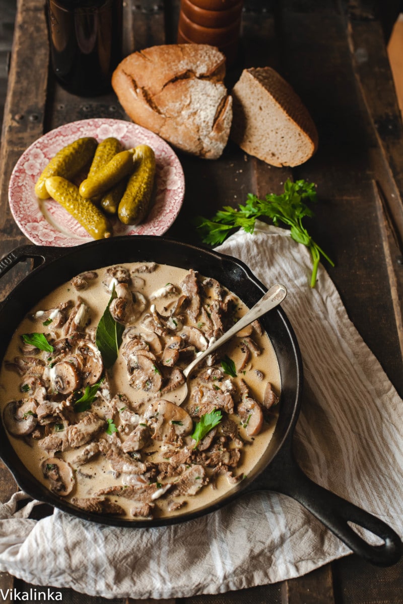 Beef Stroganoff, pickles, rye bread on a wooden table