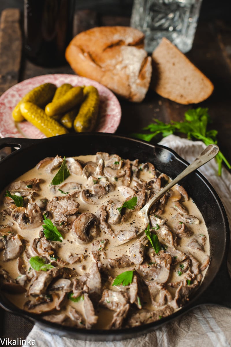 Creamy meat and mushrooms with sprinkled parsley in cast iron pan