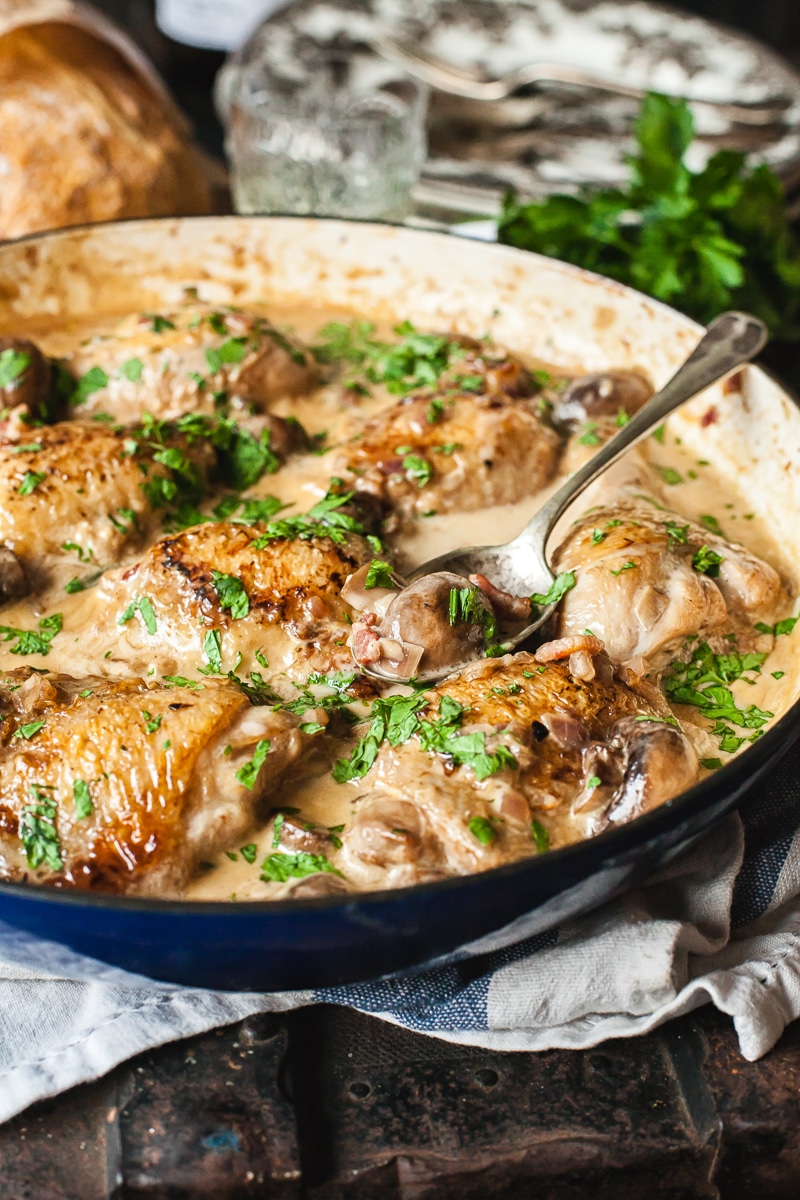 Coq au Vin Blanc in a pan with serving spoon