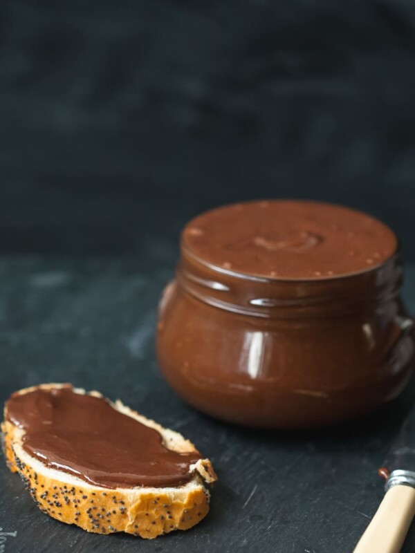 Close up of nutella on bread next to jar