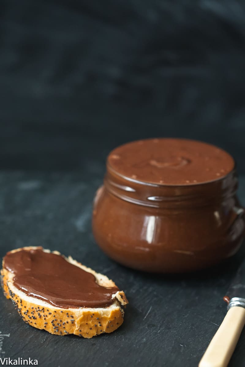 Close up of nutella on bread next to jar