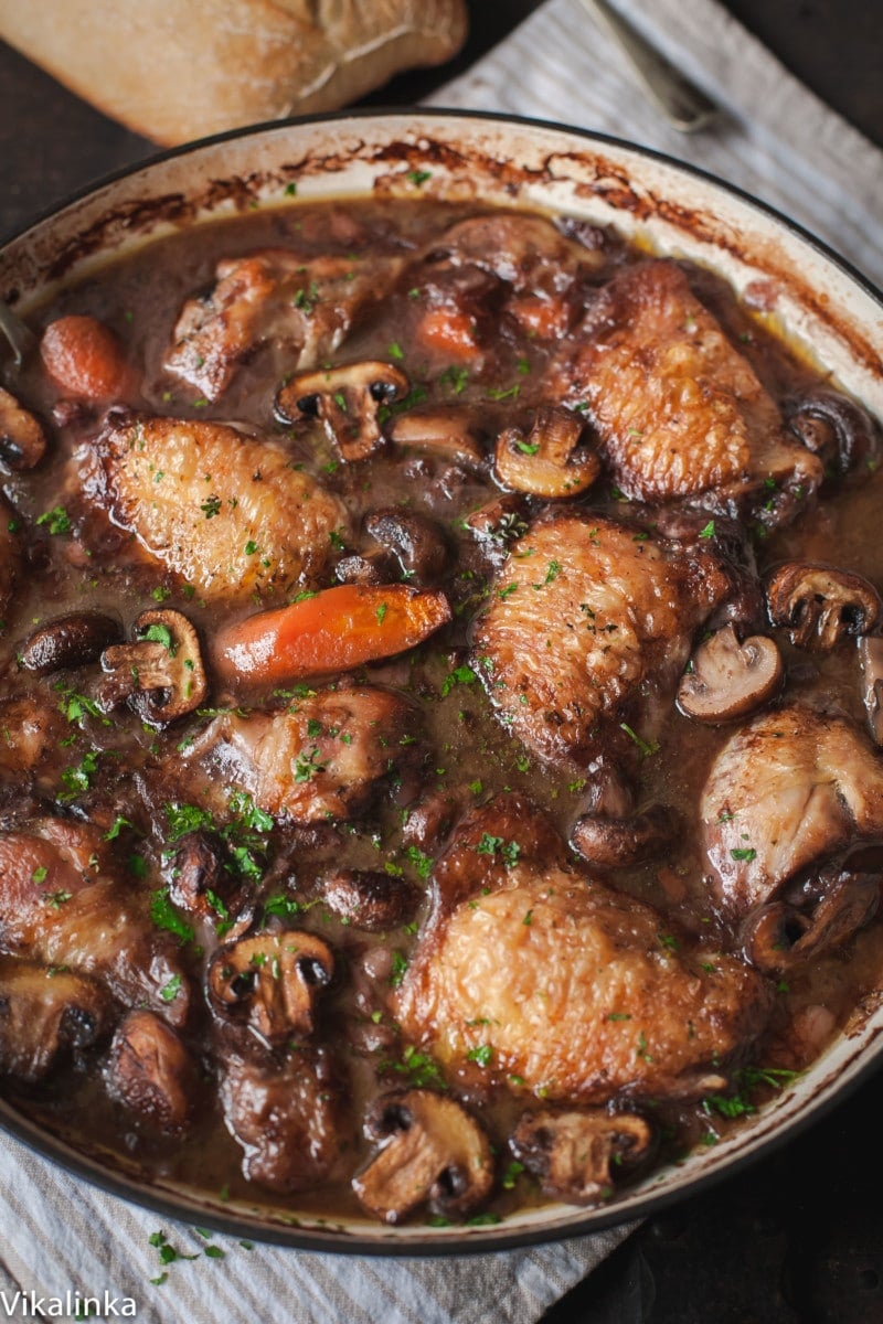 top down view of braised chicken with carrots and mushrooms in a cast iron pan