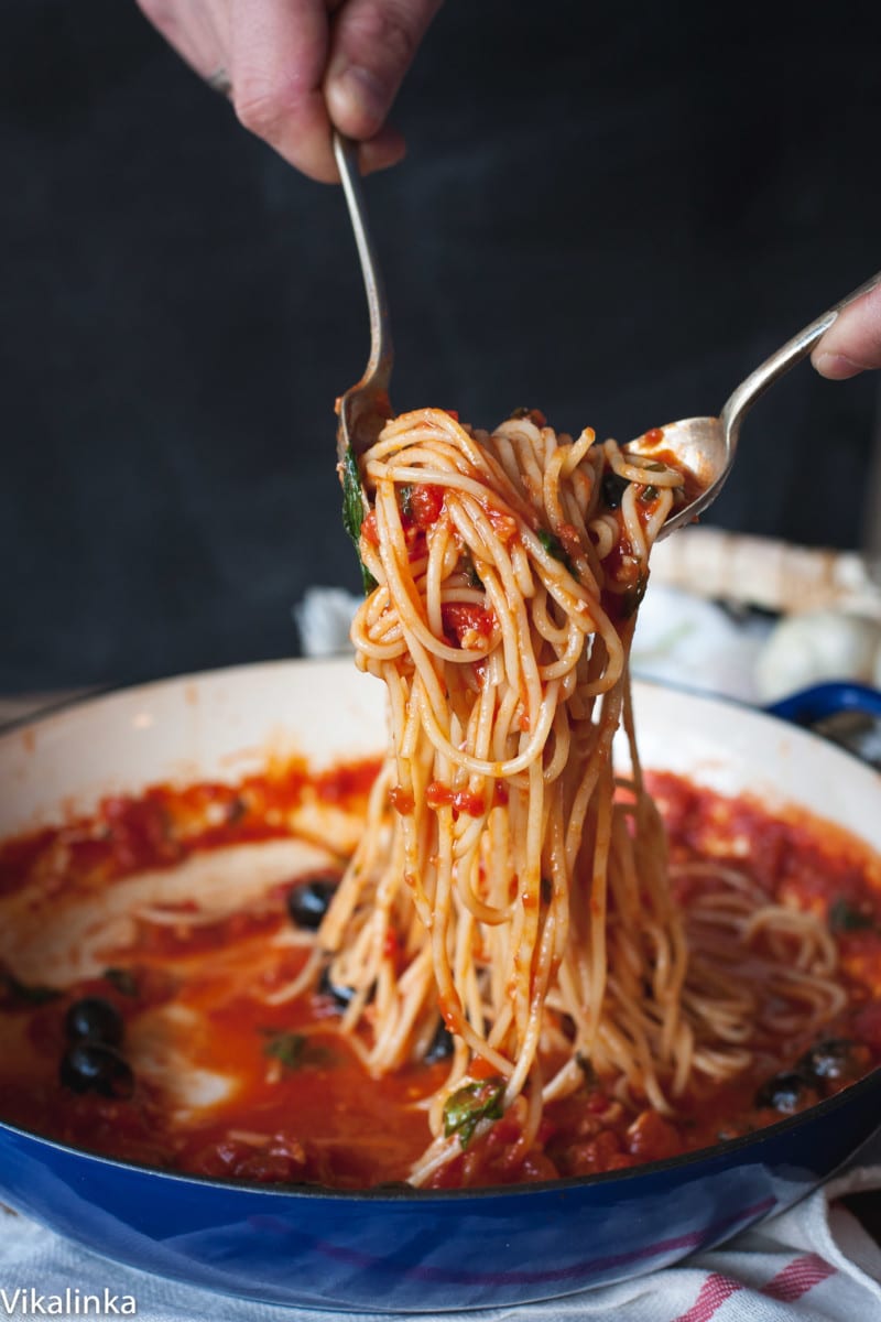 spaghetti with tomato sauce being tossed in a blue pan