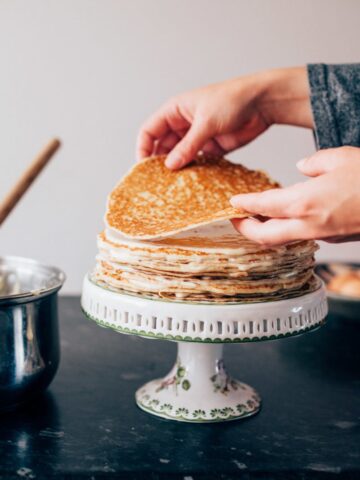 Two hands stacking pancakes