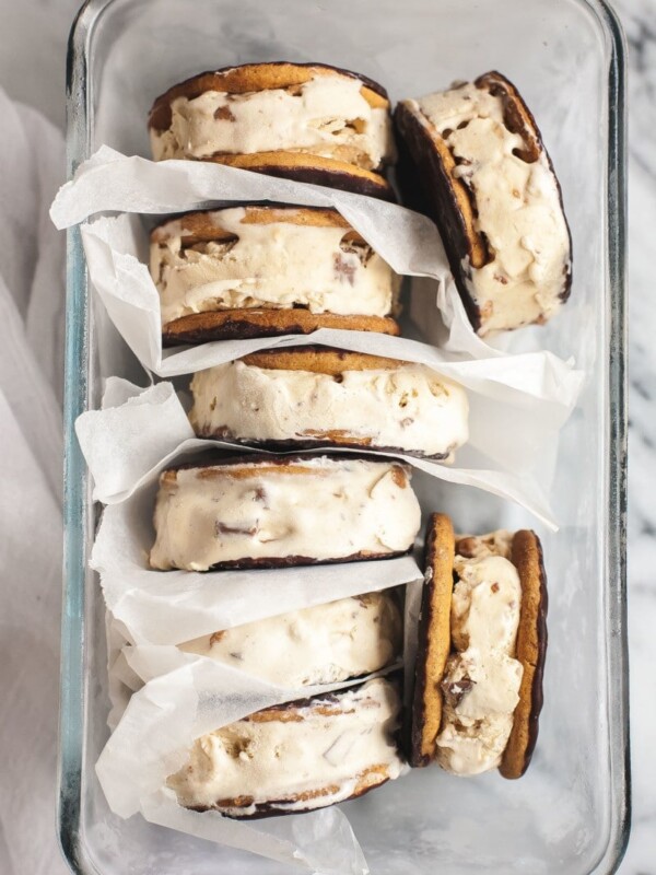 Ice cream sandwiches inside a clear dish separated by parchment paper