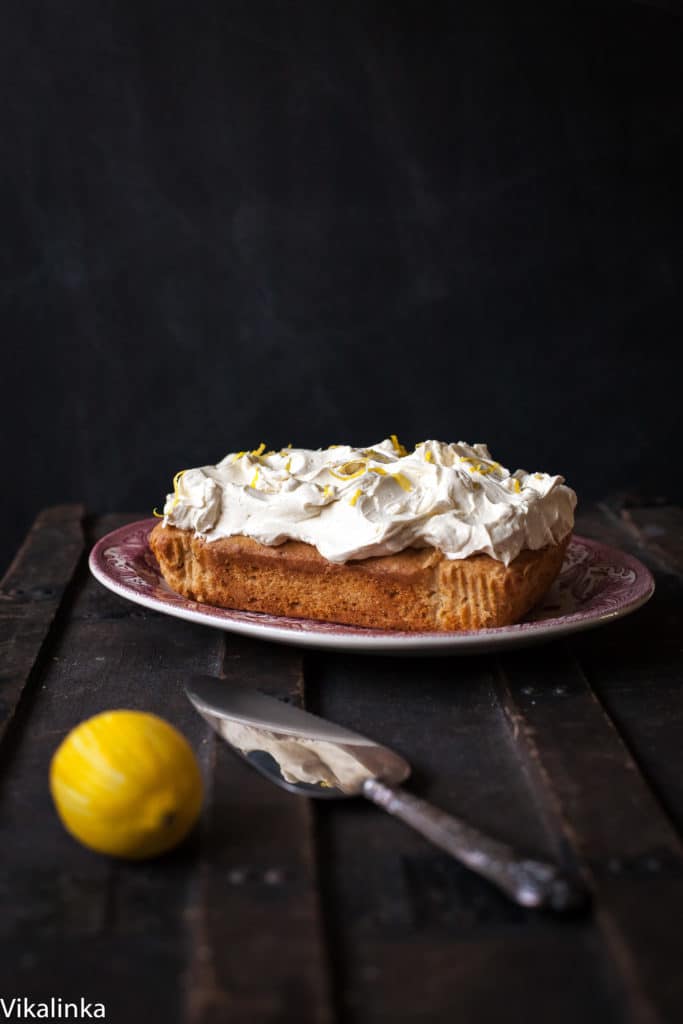 Cake on a platter beside cake slicer and lemon