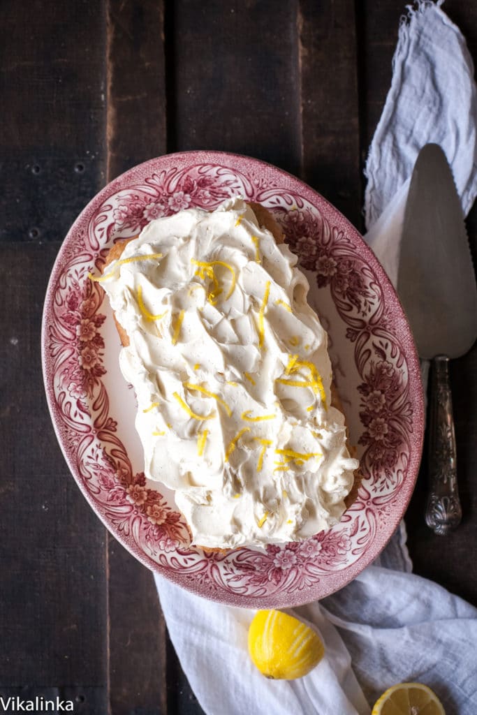 Top down view of lemon ricotta cake on a platter showing lemon zest on top of frosting