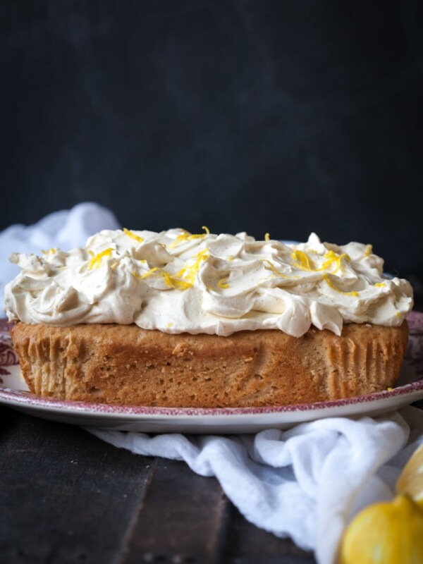 Side view of lemon ricotta cake on a plate with lemons