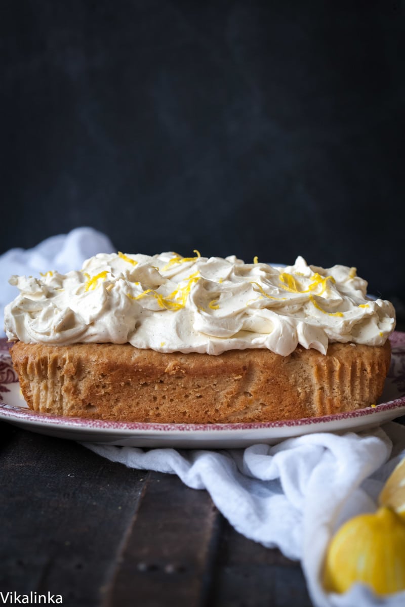 Side view of lemon ricotta cake on a plate with lemons