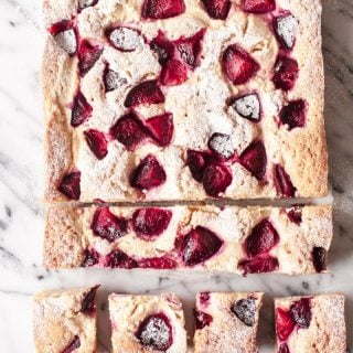 Top down view of rustic plum cheesecake with several slices cut in the end