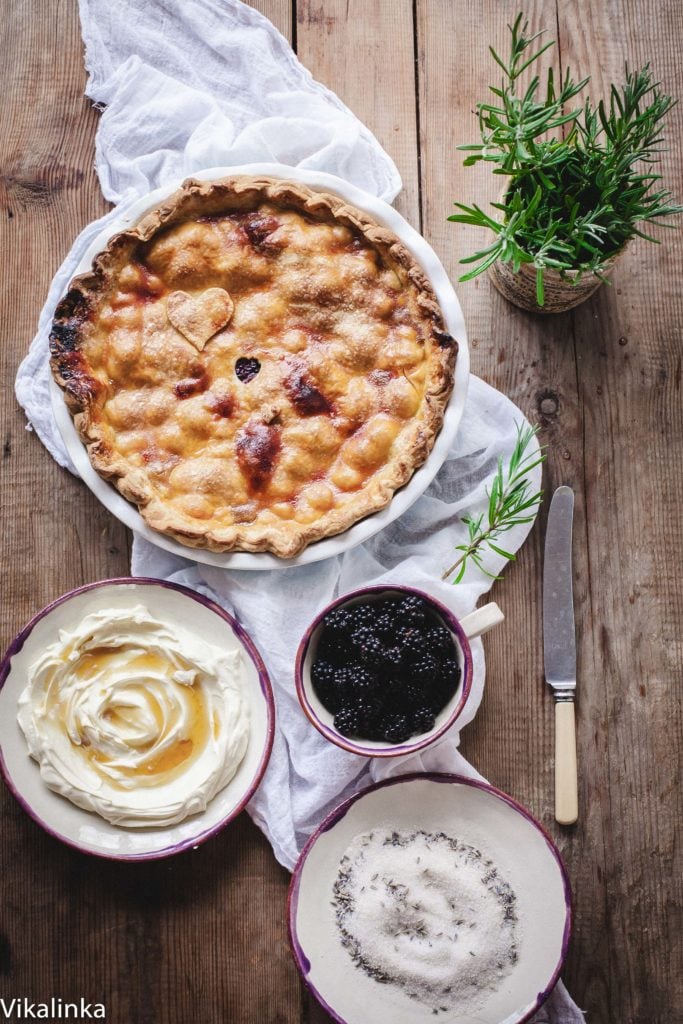 Top down view of wild blackberry pie with honeyed creme fraiche in a seperate dish along with blackberries