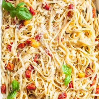 Tagliatelle tossed with roasted cherry tomato and basil sauce on a rectangular pan