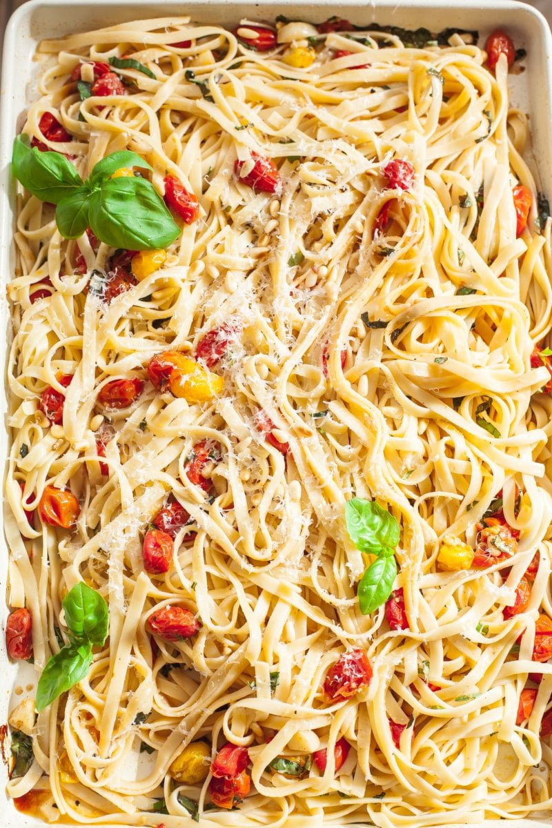 Tagliatelle tossed with roasted cherry tomato and basil sauce on a rectangular pan