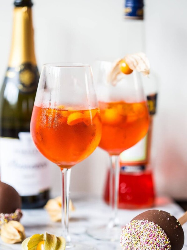 Two aperol spritz's with bottles in the background