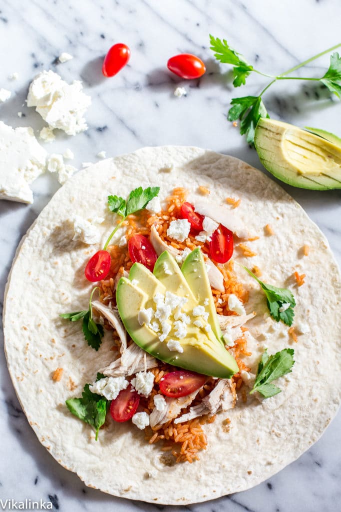 Open peri peri rice and chicken wrap on a table with extra avocado