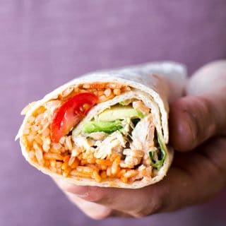 Hand holding peri peri rice and chicken wrap showing cross-section