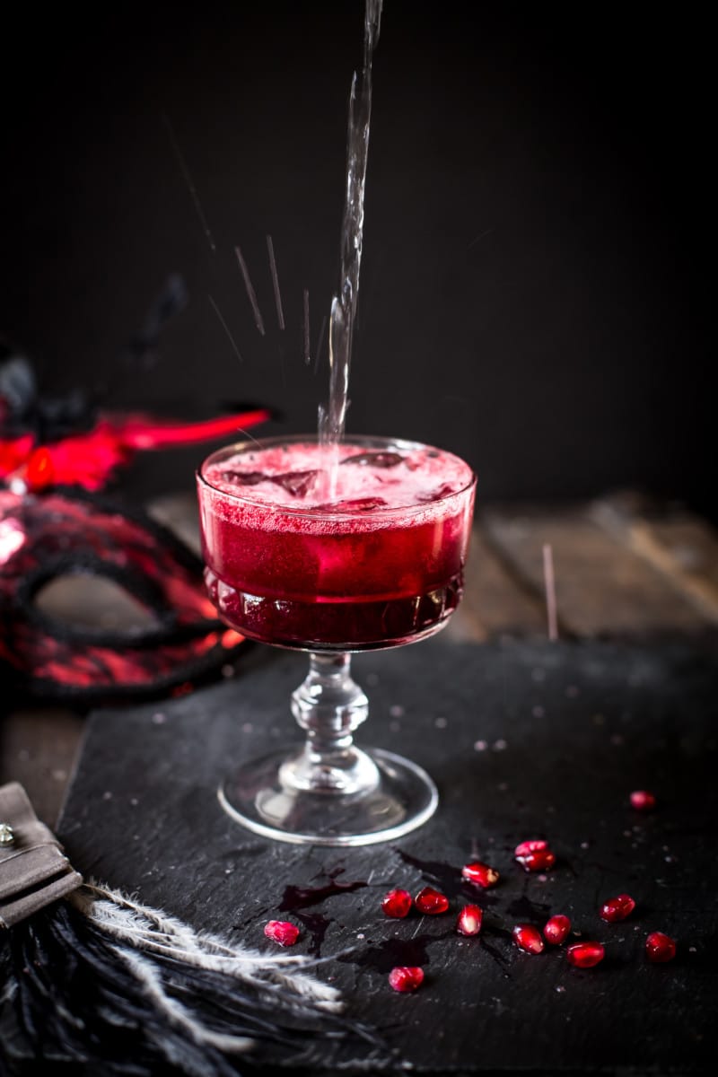 red cocktail with pomegranate seeds scattered around