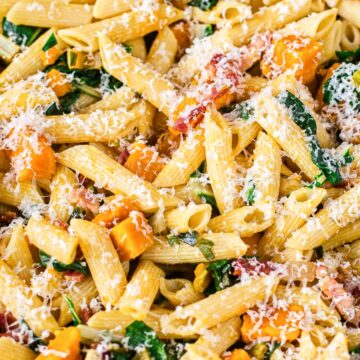 penne pasta with squash, pancetta and chard sprinkled with Parmesan closeup