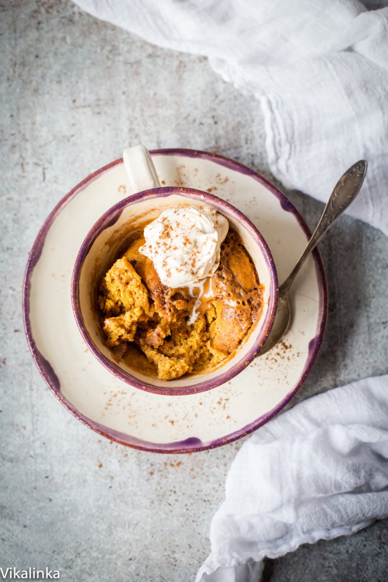 Top down view of pumpkin molten mug cake with cream and a spoon